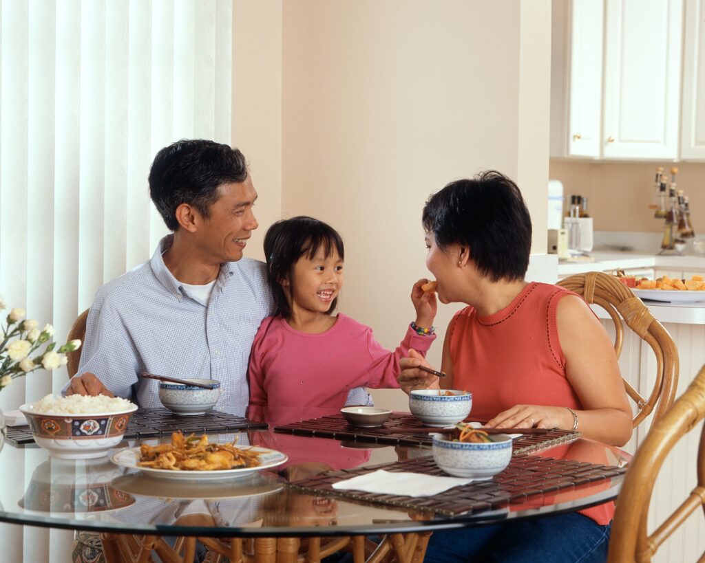 Two adults and a little girl smiling and eating together